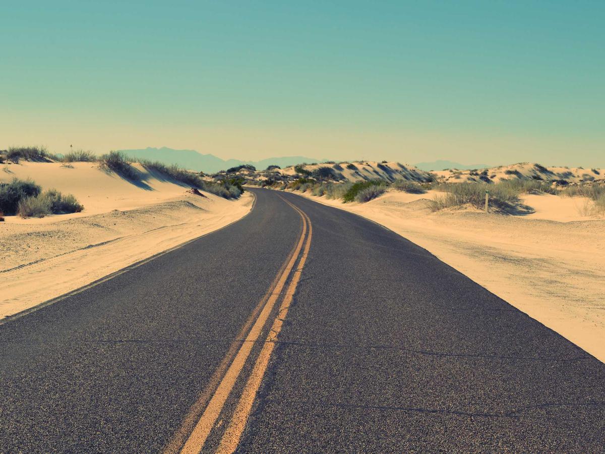 Carretera de dos carriles curvando entre dunas