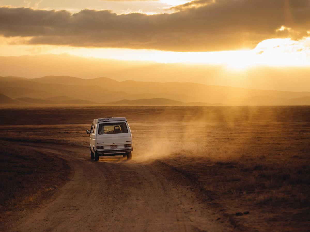 Coche por un camino de tierra al atardecer