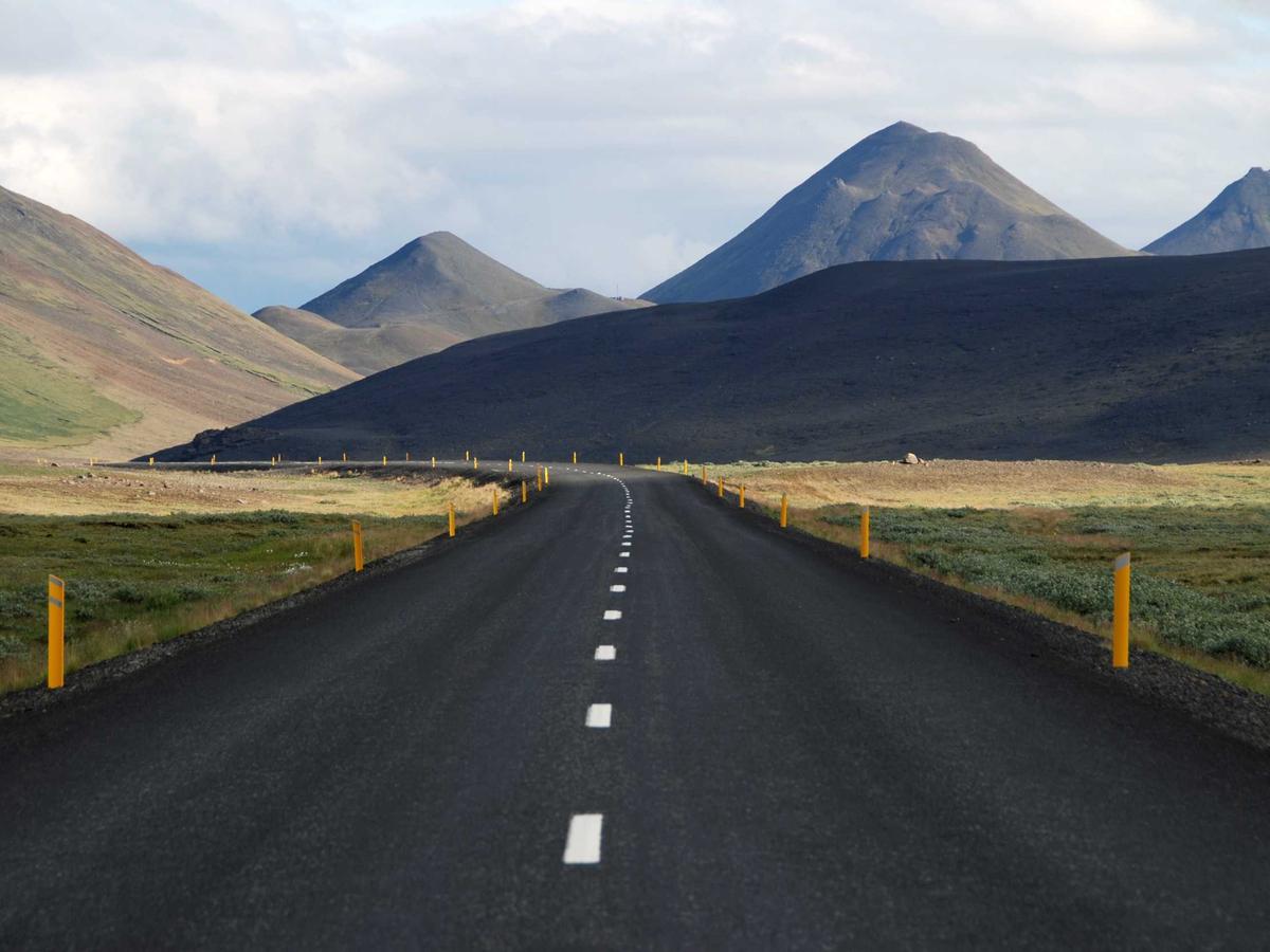 Carretera recta con línea central hacia unas montañas oscuras